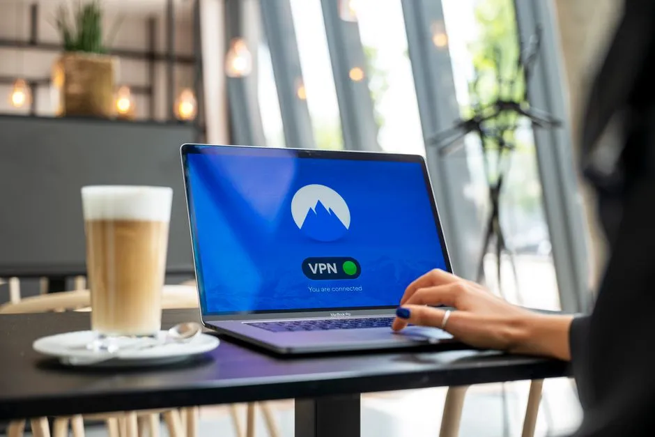 Person in a cafe using a laptop with a VPN app showing it is connected